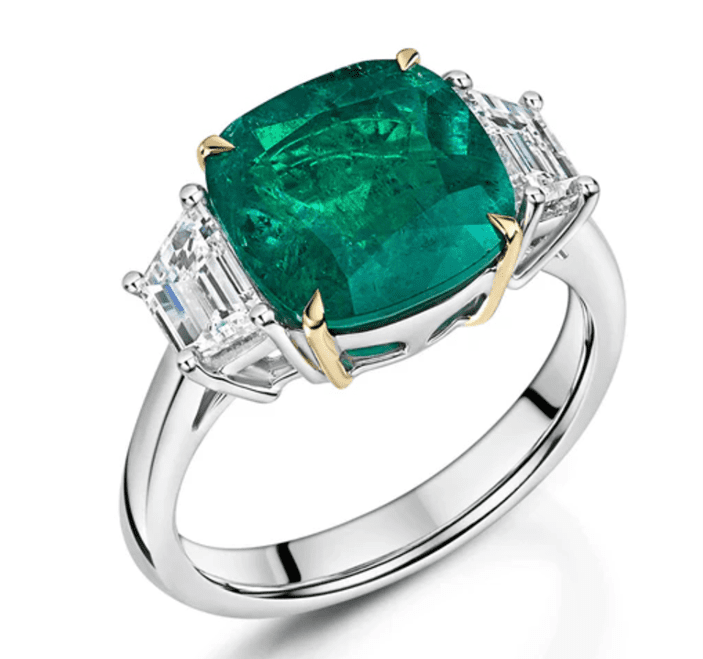 Platinum and 18ct yellow gold cushion-cut emerald and tapered baguette-cut diamond three-stone ring.